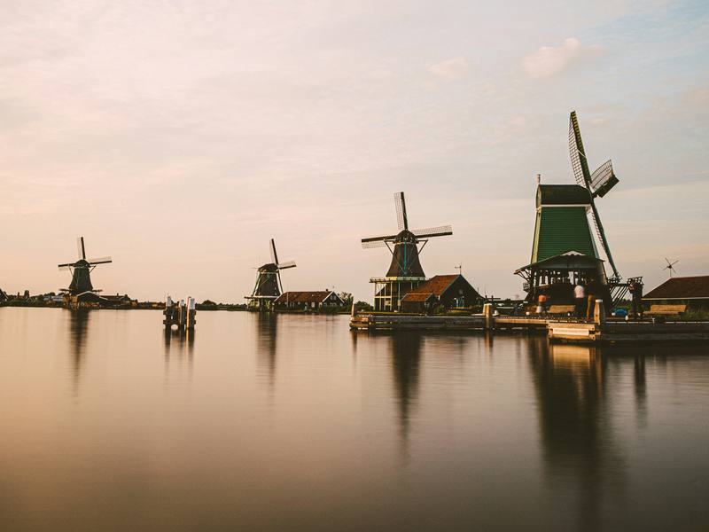 Historic Dutch windmills reflected in still water at dusk