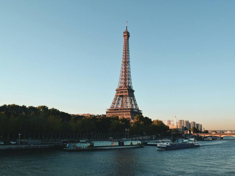 The Eiffel Tower above the Seine with river barges at golden hour