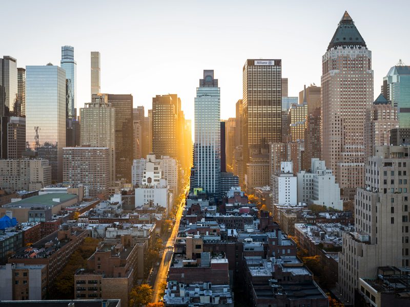 Midtown Manhattan at sunrise, low sun running straight down an avenue between the towers