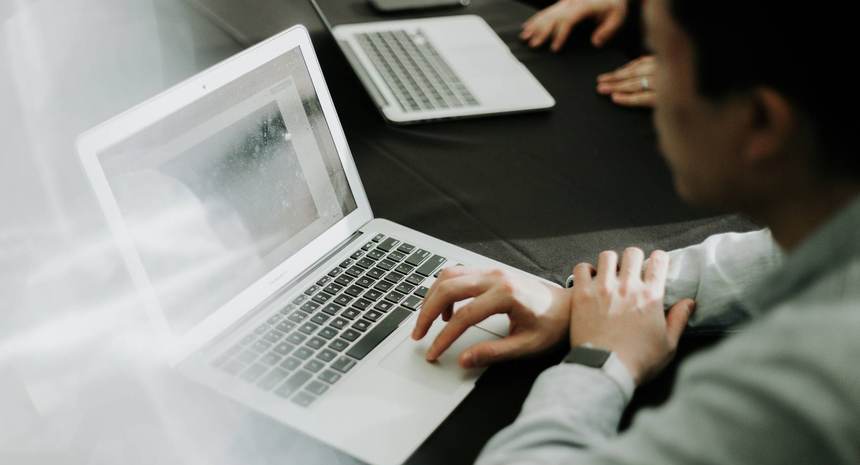 Two people working side by side at laptops